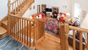 A wooden staircase leading to a living room with a fireplace, a red sofa, and a patterned rug. - 3 bedroom accommodation in Mathry, nr St Davids (Mathry, nr St Davids)