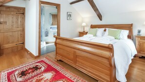 A bedroom with a wooden bed, a nightstand, a bedside table, a mirror, and a wooden wardrobe. - 3 bedroom accommodation in Mathry, nr St Davids (Mathry, nr St Davids)