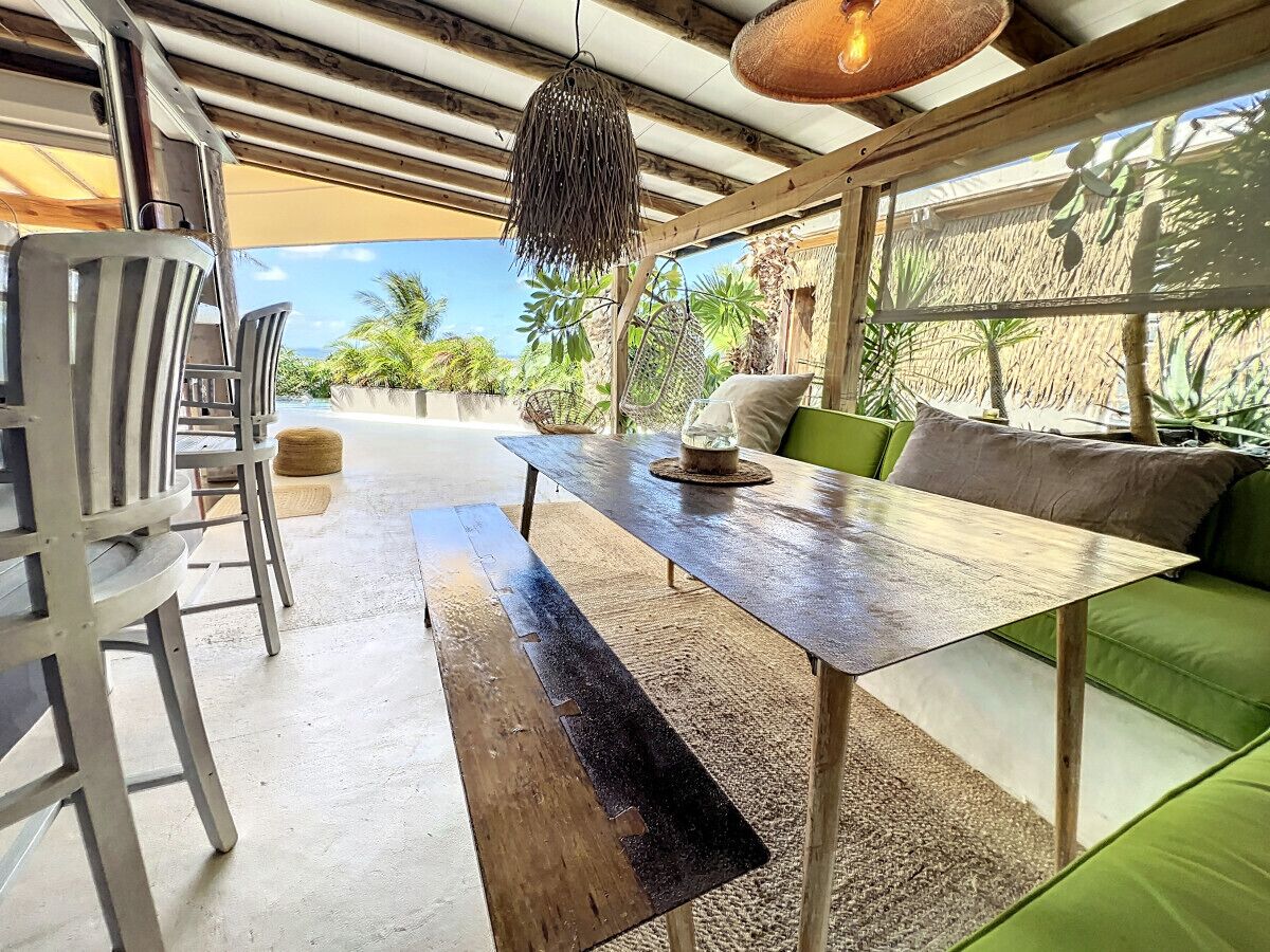 A dining area with a long wooden table, metal chairs, and a green sofa.
