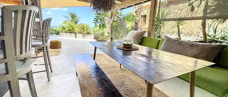 A dining area with a long wooden table, metal chairs, and a green sofa.