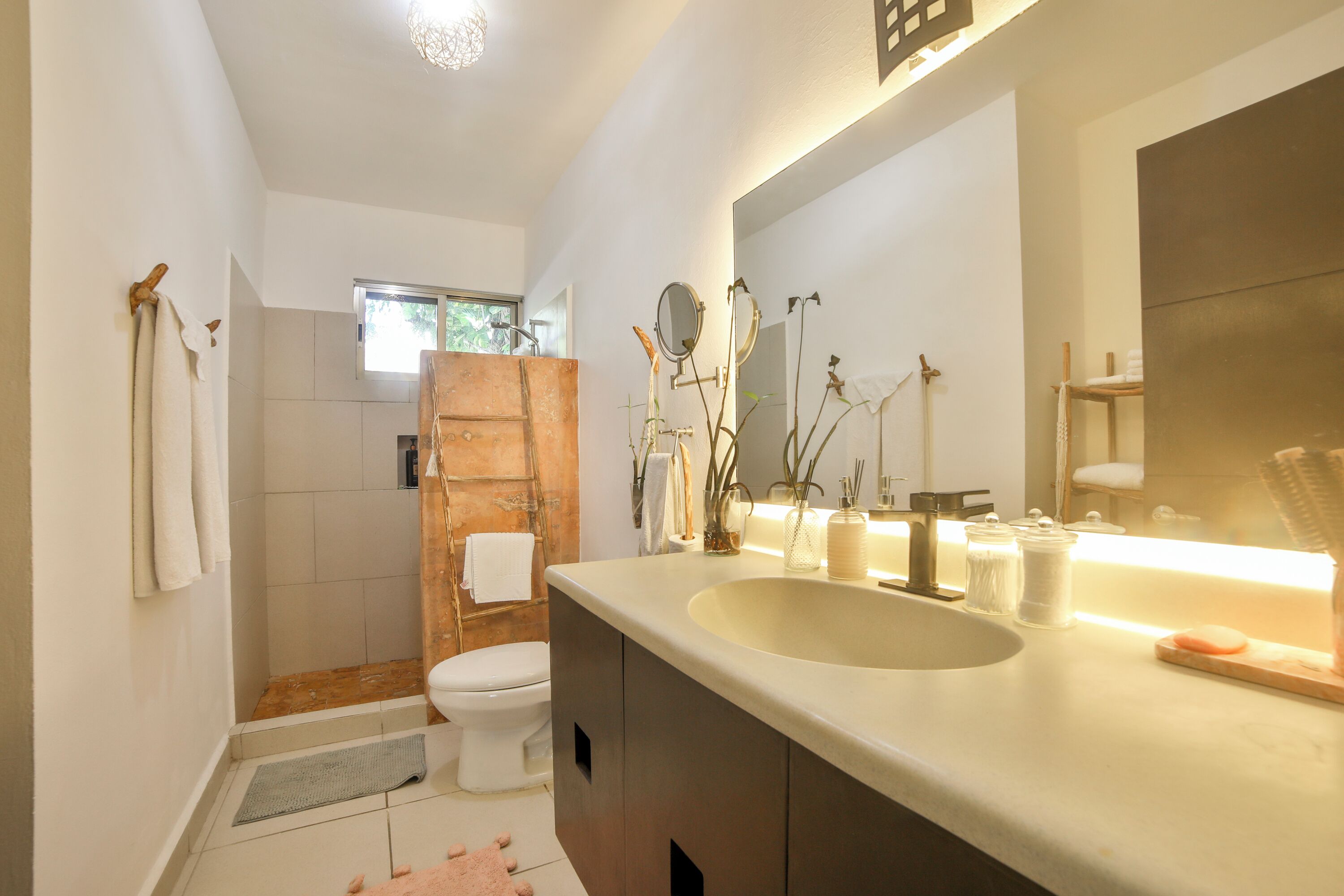 A modern bathroom with a large sink, a mirror, and a toilet.