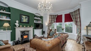 A traditional living room with a fireplace, leather sofa, and a chandelier.