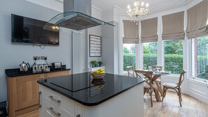 A modern kitchen with a black countertop, wooden cabinets, and a central island with a bowl of fruit.