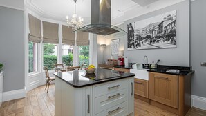 A modern kitchen with a central island, wooden cabinets, and a large window with curtains.