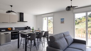 Une cuisine moderne avec un coin repas, un canapé gris et un balcon avec vue.