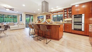 Una cocina moderna con armarios de madera, una isla central con taburetes altos y un horno grande.