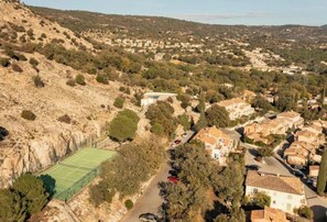 Residents can enjoy a peaceful game of tennis on the court surrounded by lush trees and rolling hills.