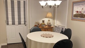 Ein Essbereich mit einem runden Tisch, Stühlen, einer Chandelier, einer Lampe und einer Tür mit gestreiften Vorhängen.