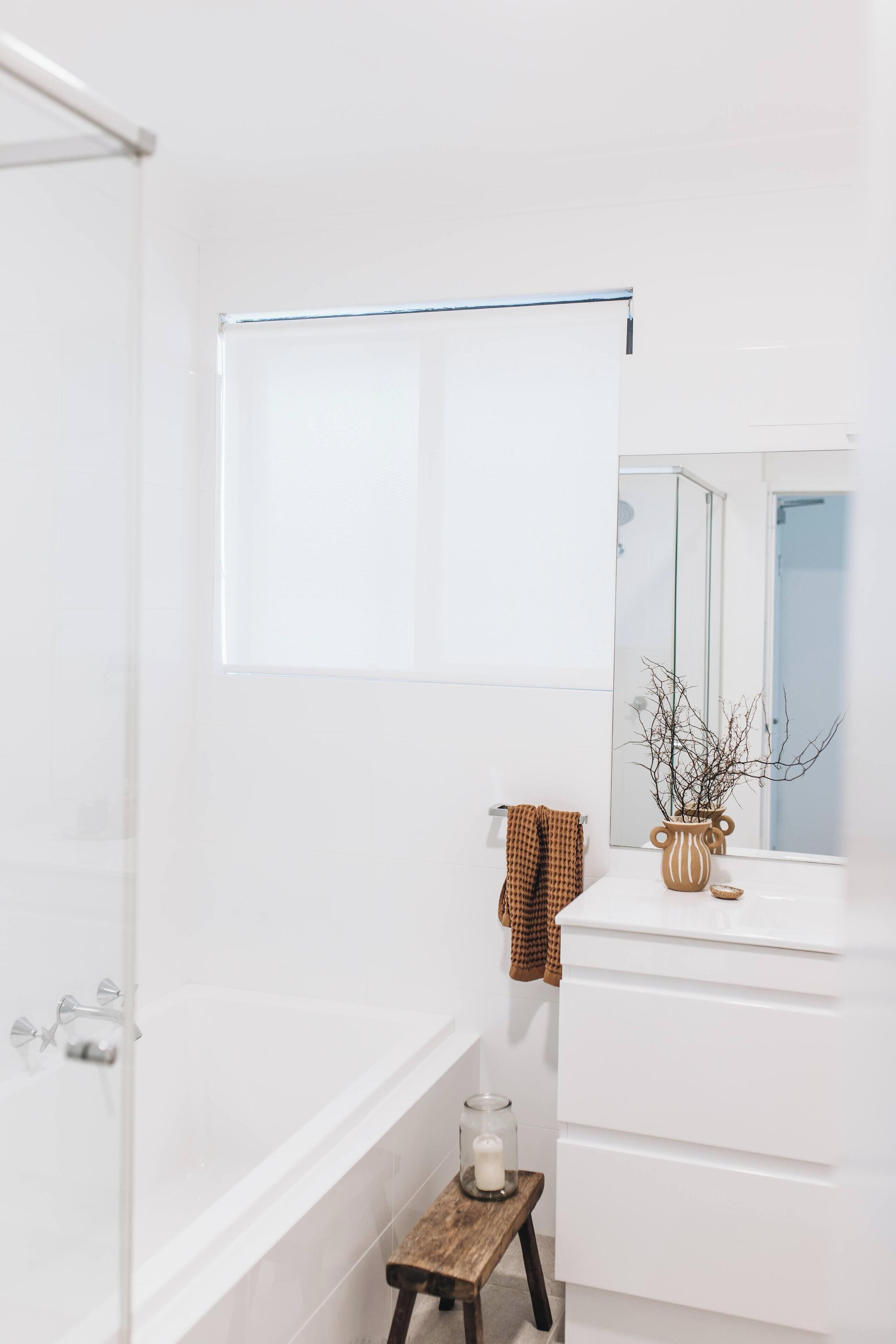 A bathroom with a bathtub, a mirror, a towel rack, and a small wooden stool.