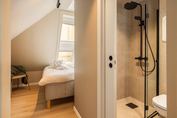 A bedroom with a bed, a chair, a shower, and a toilet. - Explore Bergen | 24/7 Self check-in | 500m Torget (Bergenhus)