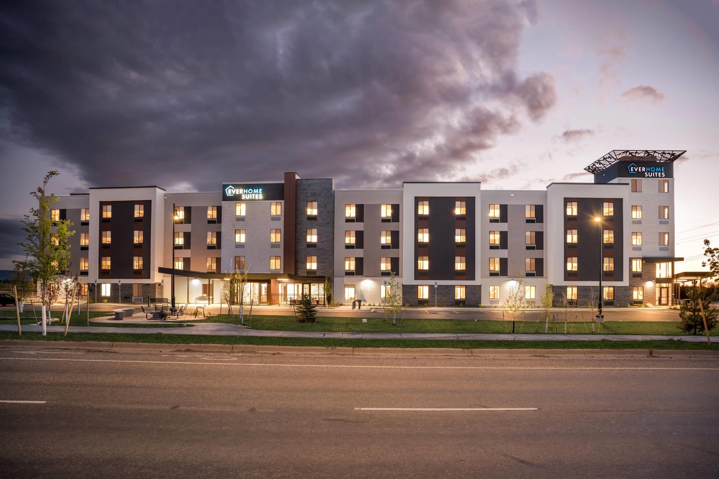 Ett modernt hotell med flera våningar, uteservering och en väl upplyst entré.