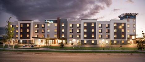 Um hotel moderno com vários andares, área externa para sentar e uma entrada bem iluminada.