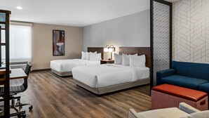 A hotel room with two beds, a desk, a chair, a sofa, and a small table. - Everhome Suites Bozeman (Bozeman)