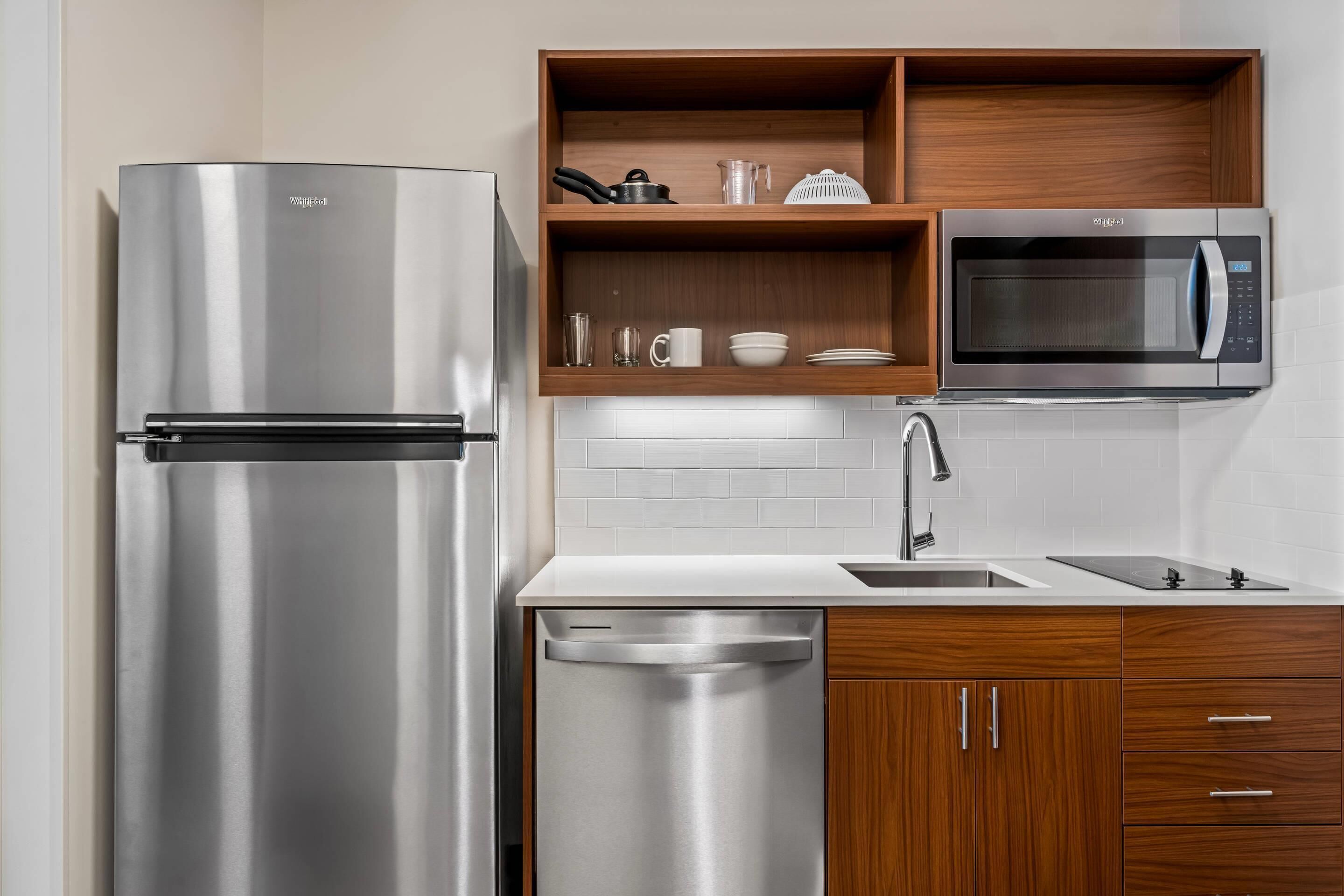 A modern kitchen with a stainless steel refrigerator, a built-in microwave, and wooden cabinetry.