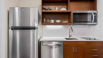 A modern kitchen with a stainless steel refrigerator, a built-in microwave, and wooden cabinetry.