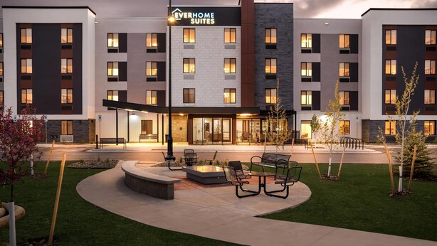 A modern hotel with multiple floors, outdoor seating, and a well-lit entrance. - Everhome Suites Bozeman (Bozeman)