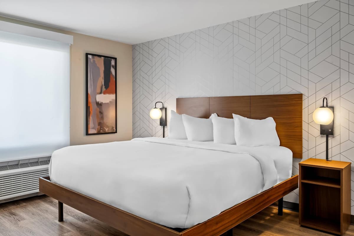 A modern hotel room with a large bed, two bedside tables, and a geometric-patterned wall.