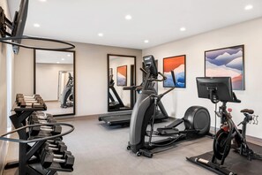 A gym with treadmills, an elliptical, a stationary bike, and a weight rack. - Everhome Suites Bozeman (Bozeman)