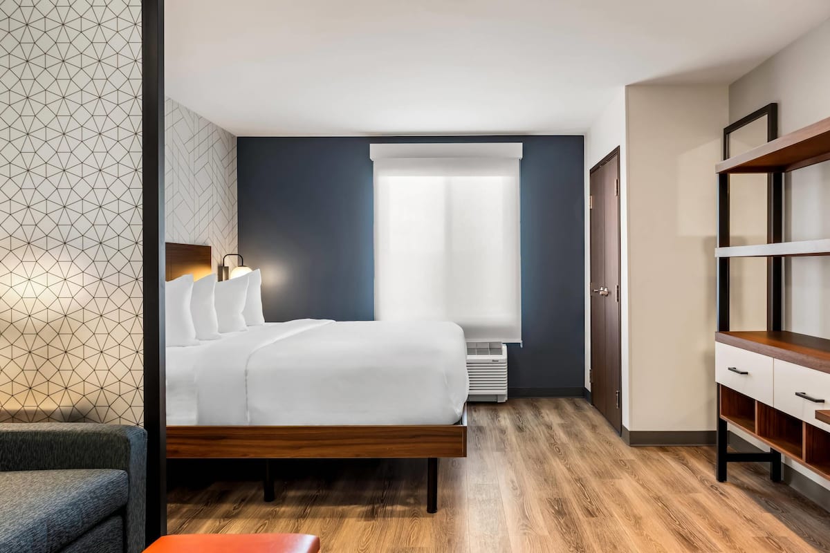 A modern hotel room with a bed, bedside table, and a wardrobe.