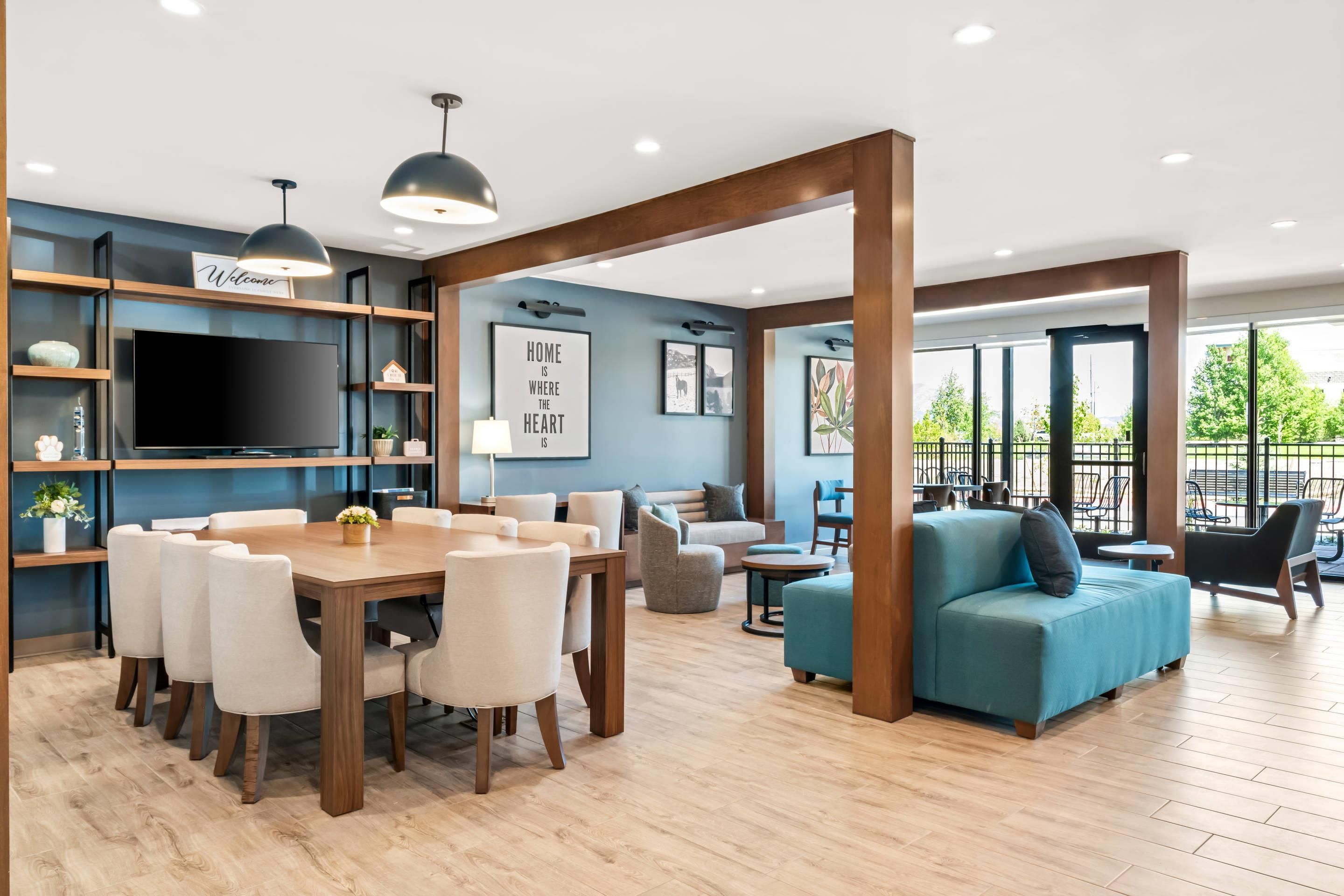 A modern living room with a dining area, a blue sofa, and a large TV.