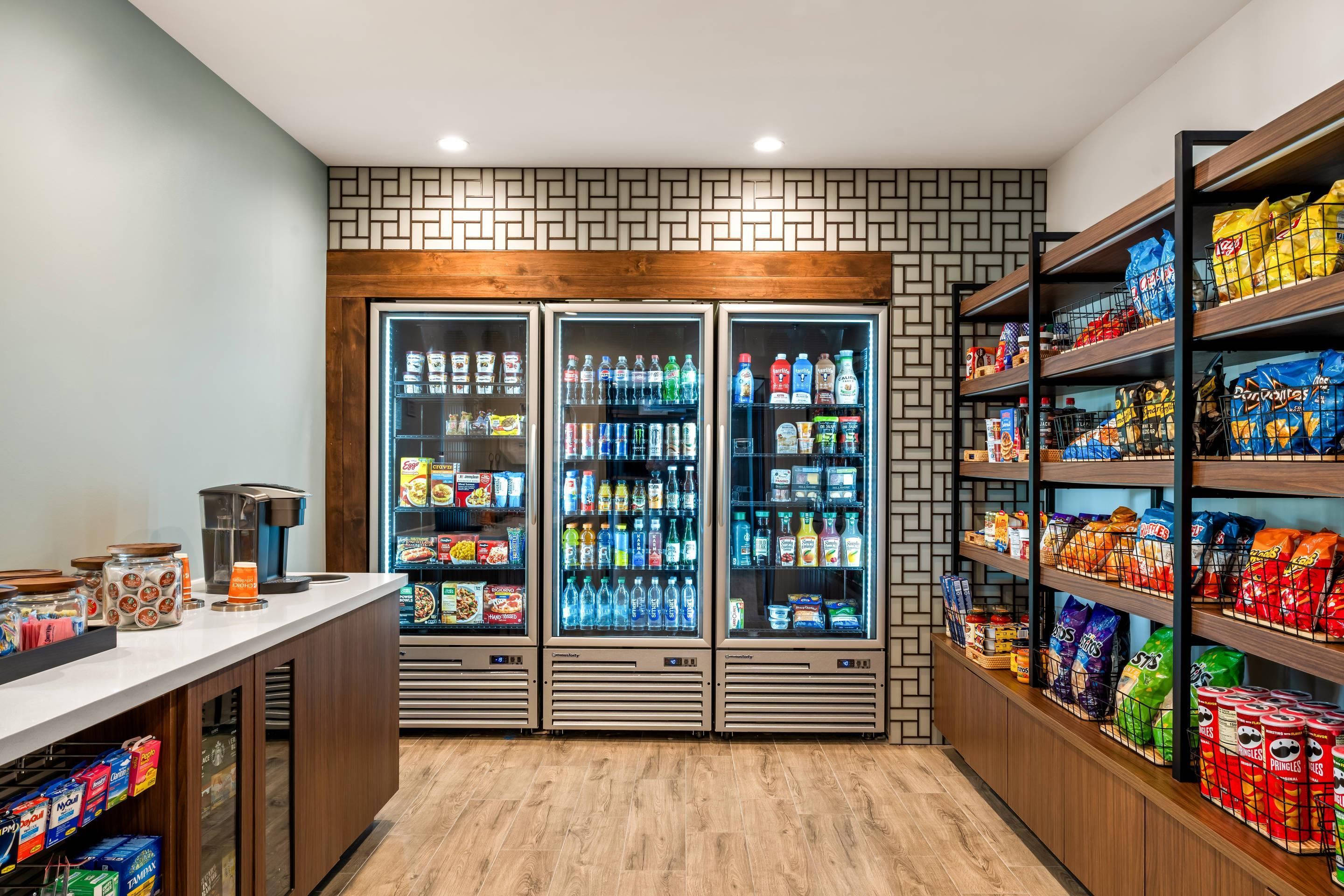 Een bedieningspunt voor zelfbediening met gekoelde drankautomaten en schappen voor snacks.