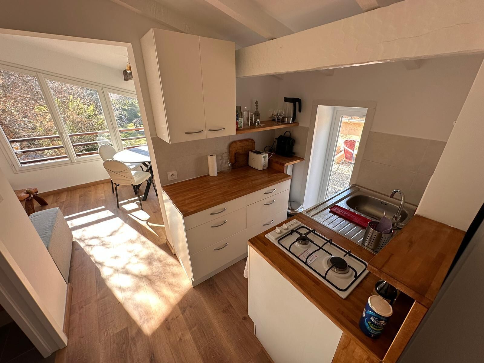 A compact kitchen with a gas stove, a sink, and a window overlooking a garden.