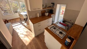 Una cocina compacta con estufa a gas, un lavamanos y ventana con vistas a un jardín.