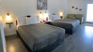 Une chambre d’hôtel avec deux lits, un tableau au mur, une chaise et une lampe.