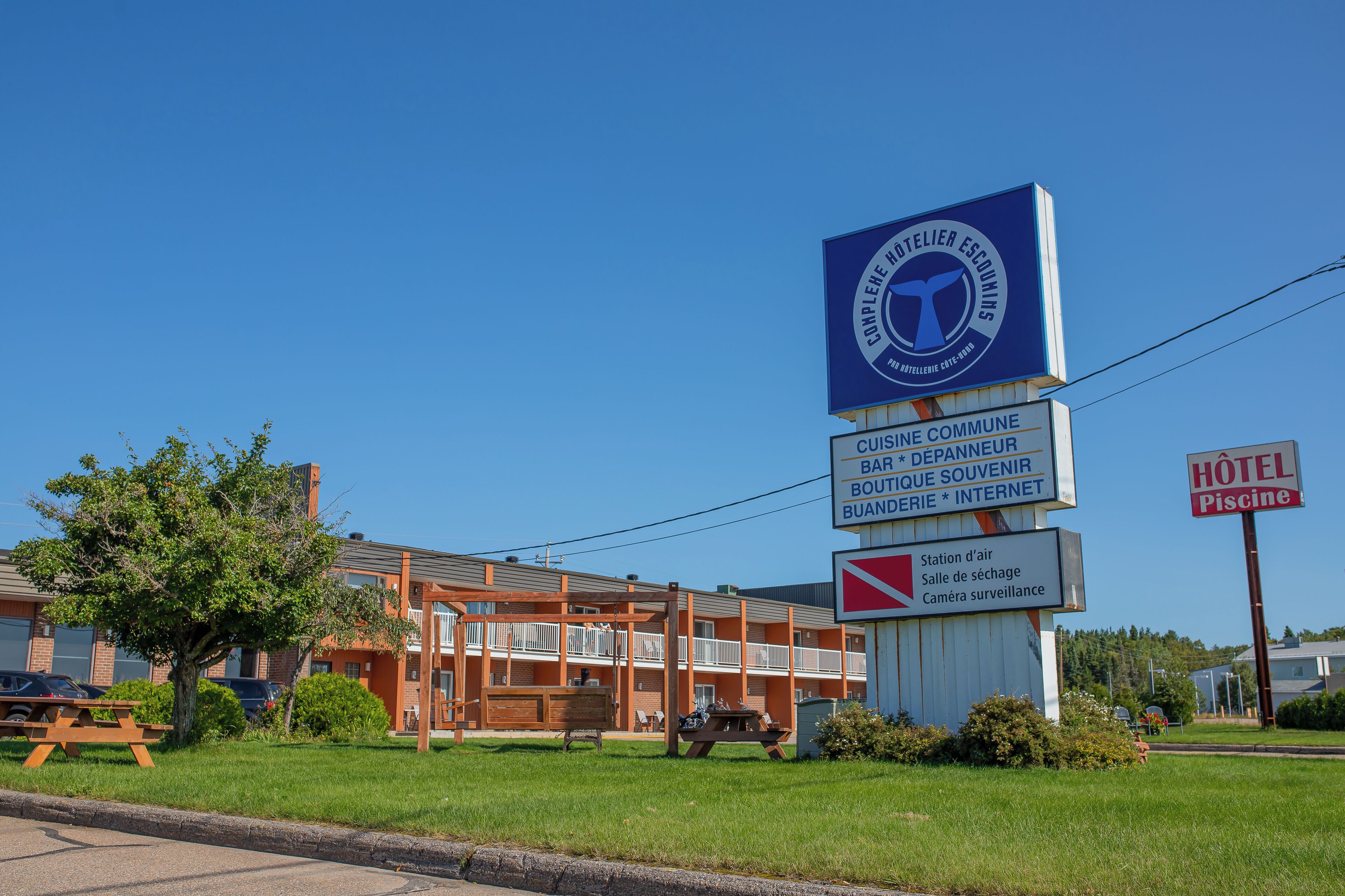 A hotel with a blue sign indicating amenities like a bar, souvenir shop, and internet.