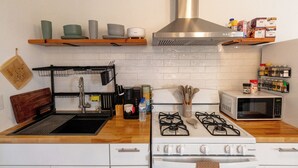 A kitchen with a gas stove, microwave, and a coffee maker on the counter.