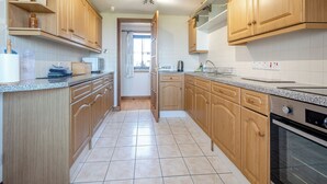 A kitchen with wooden cabinets, a granite countertop, a stainless steel oven, and a window with a view. - Barnstable - UK46888 (Shannochie)