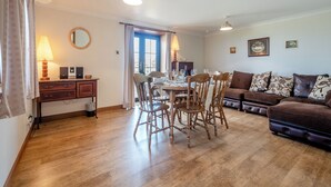 A dining area with wooden chairs and a table, a sofa, and a lamp on a desk. - Barnstable - UK46888 (Shannochie)