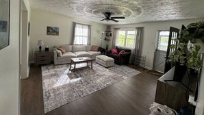 Un salon spacieux doté d’un ventilateur de plafond, de deux canapés, d’une table basse et d’un grand tapis.