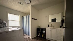 Une buanderie équipée d’un lave-linge, d’un étendoir et d’un espace douche avec un rideau.