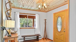 Ein Zimmer mit einer Holzbänken, einer Holztür mit Glasfenster, einer Holzboden und einer Bank mit einer Lampe und Dekoration.