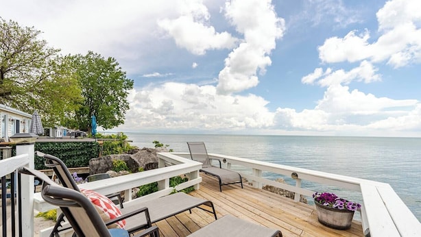 Een houten terras met zitplaatsen buiten, een leuning en uitzicht op het water.