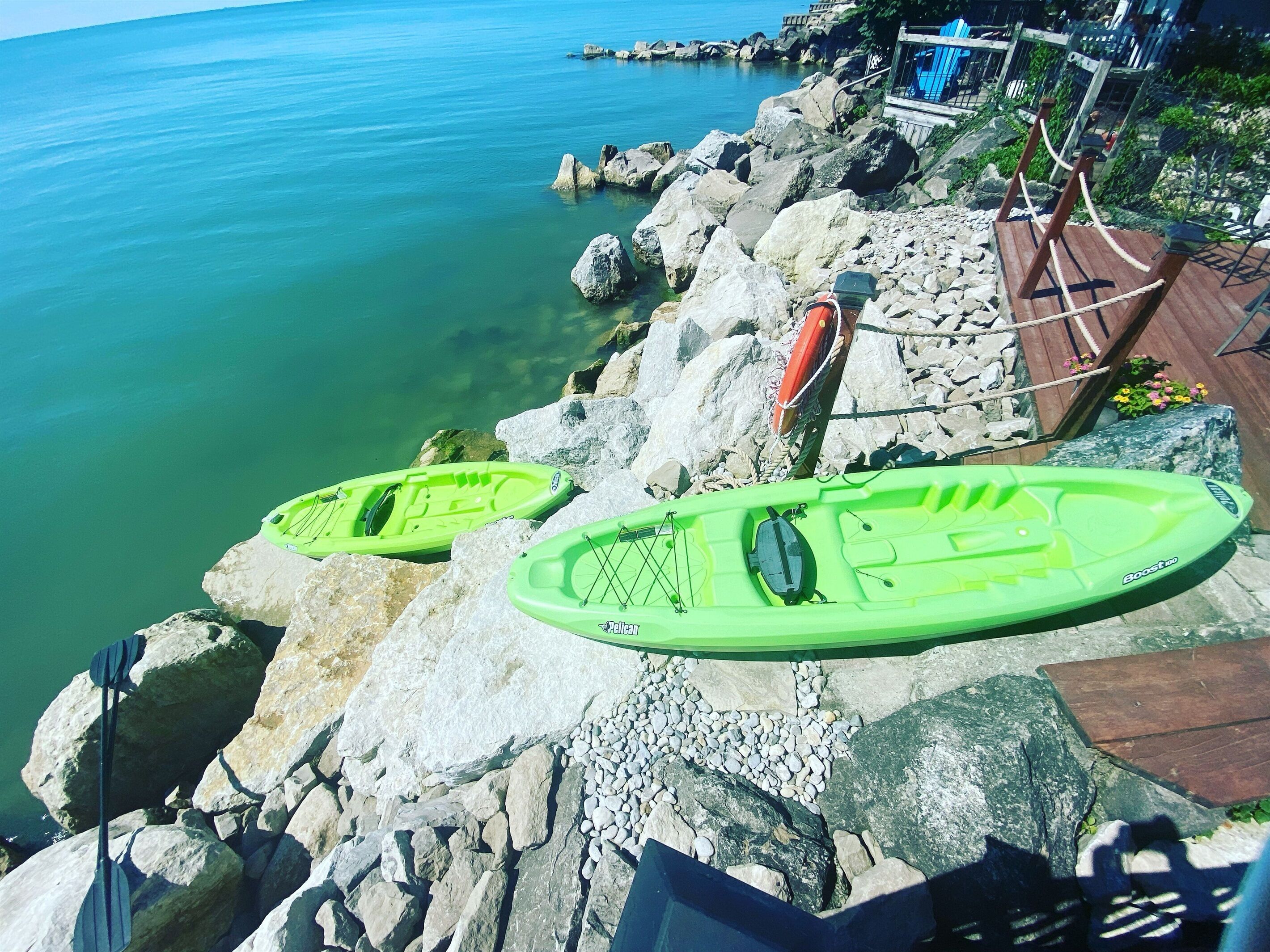 Kayaks on a rocky shore with a view of the sea.