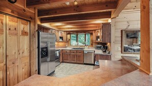Una cocina moderna con armarios de madera, un refrigerador de acero inoxidable, horno empotrado y un ventanal con vistas al exterior.