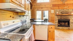 Una cocina con armarios de madera, estufa, lavavajillas y chimenea de piedra.