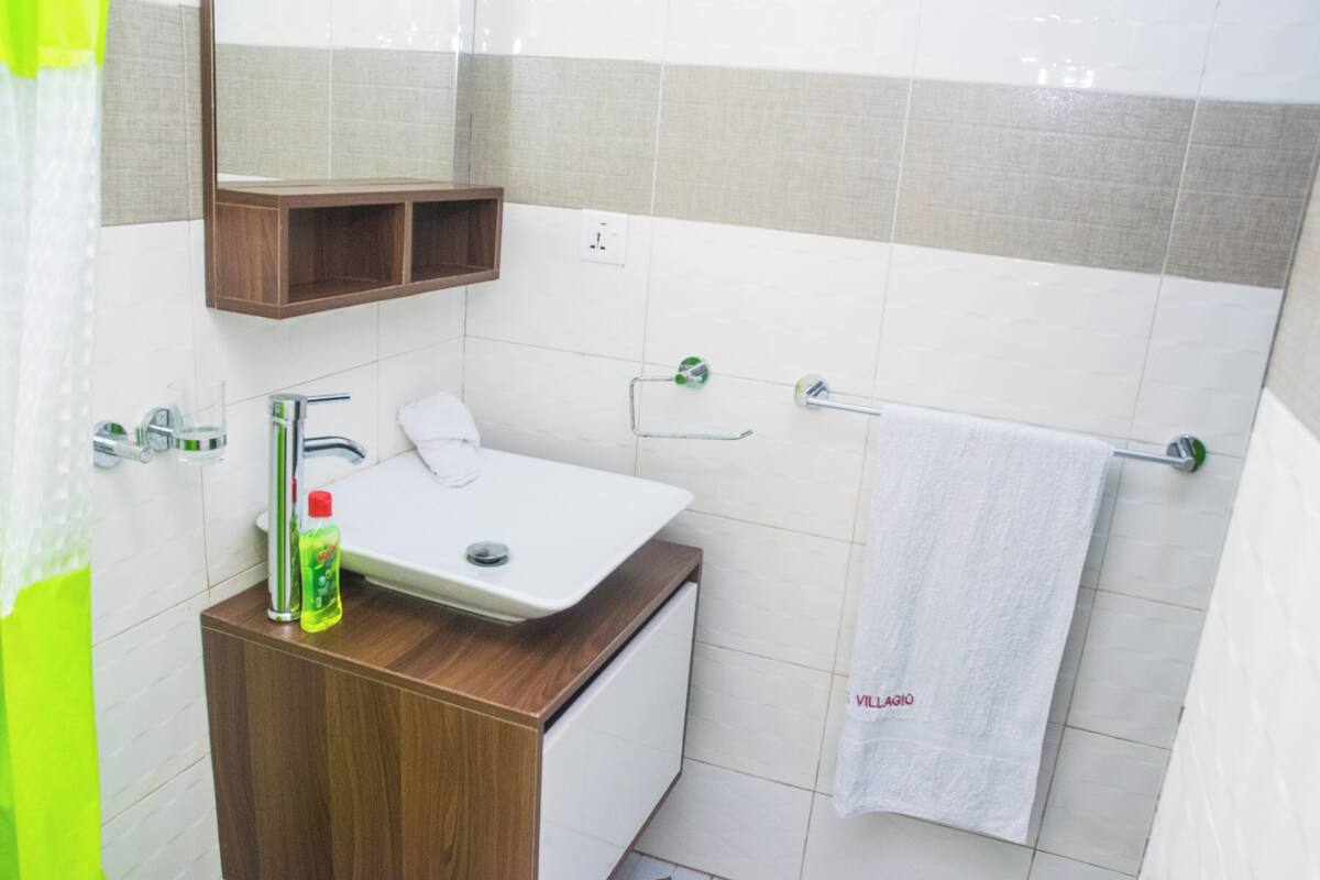 Une salle de bain avec un lavabo blanc, un meuble-lavabo en bois, un miroir et une serviette suspendue à un porte-serviettes.