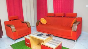 A room with a red sofa set, a wooden coffee table, and a green rug.