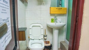 A small bathroom with a toilet, sink, and a wooden cabinet above the sink.