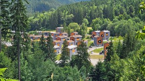 A residential area with modern multi-story buildings surrounded by dense forest and mountains. - Chalets Hrabovo (Ruzomberok)