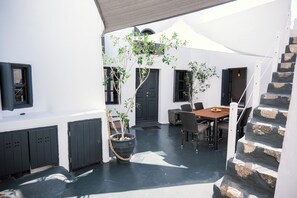 A courtyard with a wooden table and chairs, a potted plant, and a staircase.