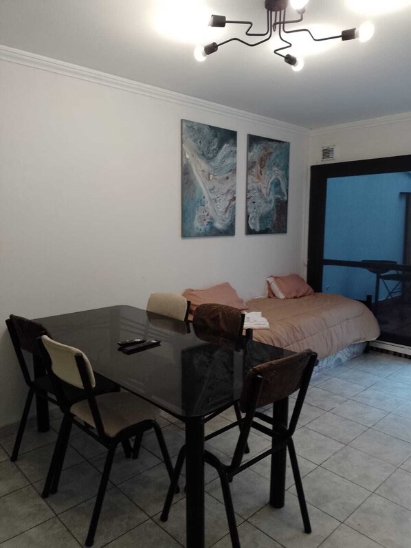 Cozy retreat with a dining table, comfortable bed, and a large window offering a view of the outside.