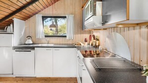Cocina pequeña con paredes de madera, una ventana y estufa integrada.