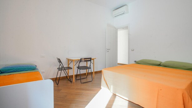 A room with a bed, a small table with chairs, and a wardrobe.