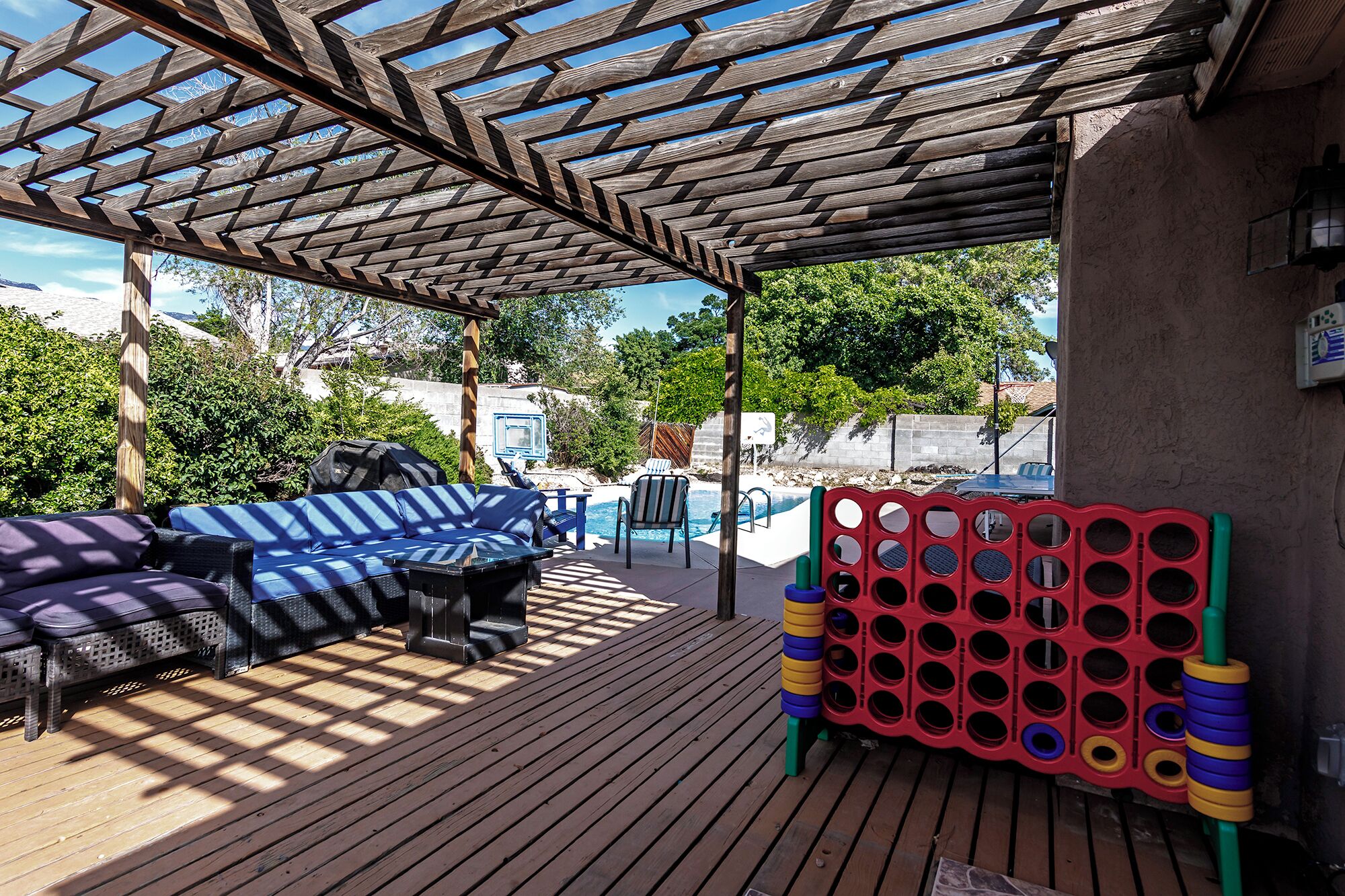 A covered outdoor area with a pool, lounge chairs, and a children's play structure.