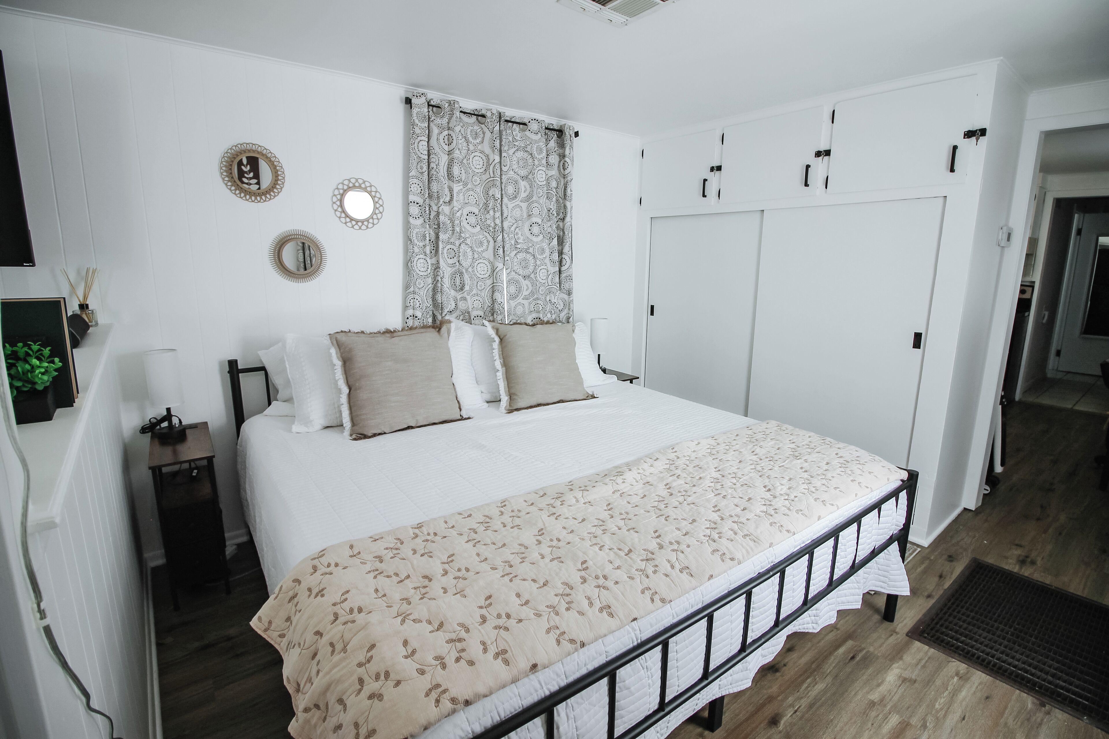 Una camera da letto ordinata con un letto, comodini, un armadio e uno specchio appeso al muro.