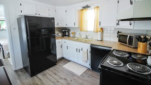 Una cocina moderna con armarios blancos, un refrigerador negro, una estufa y un microondas.